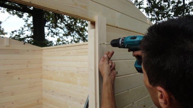 Vissage du cadre de porte d'un abri de jardin en bois Habrita
