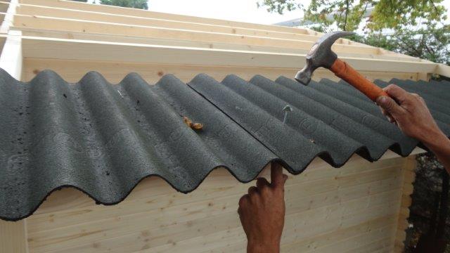 Vissage du toit ondulé d'un abri de jardin sur les crêtes des ondulations